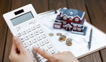 female-hand-operating-calculator-front-villa-house-model.jpg