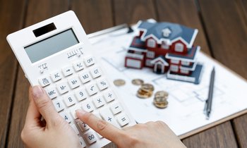 female-hand-operating-calculator-front-villa-house-model.jpg