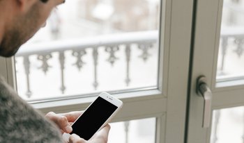 janelas segurança FREEPIK homem-sem-rosto-usando-o-smartphone-perto-da-janela.jpg